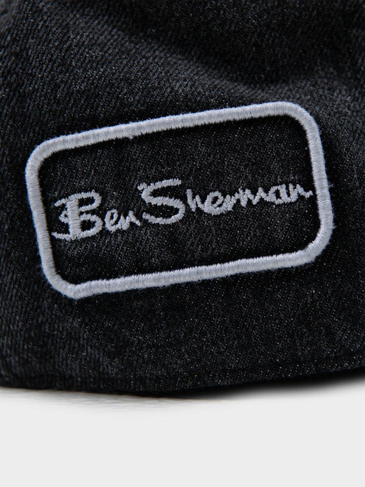 Close-up of Ben Sherman embroidered logo patch on black denim Dixie Cap