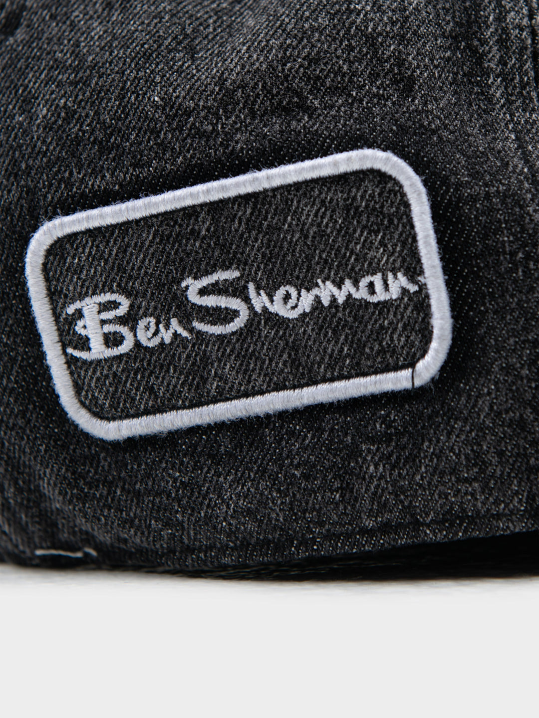 Close-up of Ben Sherman embroidered logo patch on charcoal denim Dixie Cap