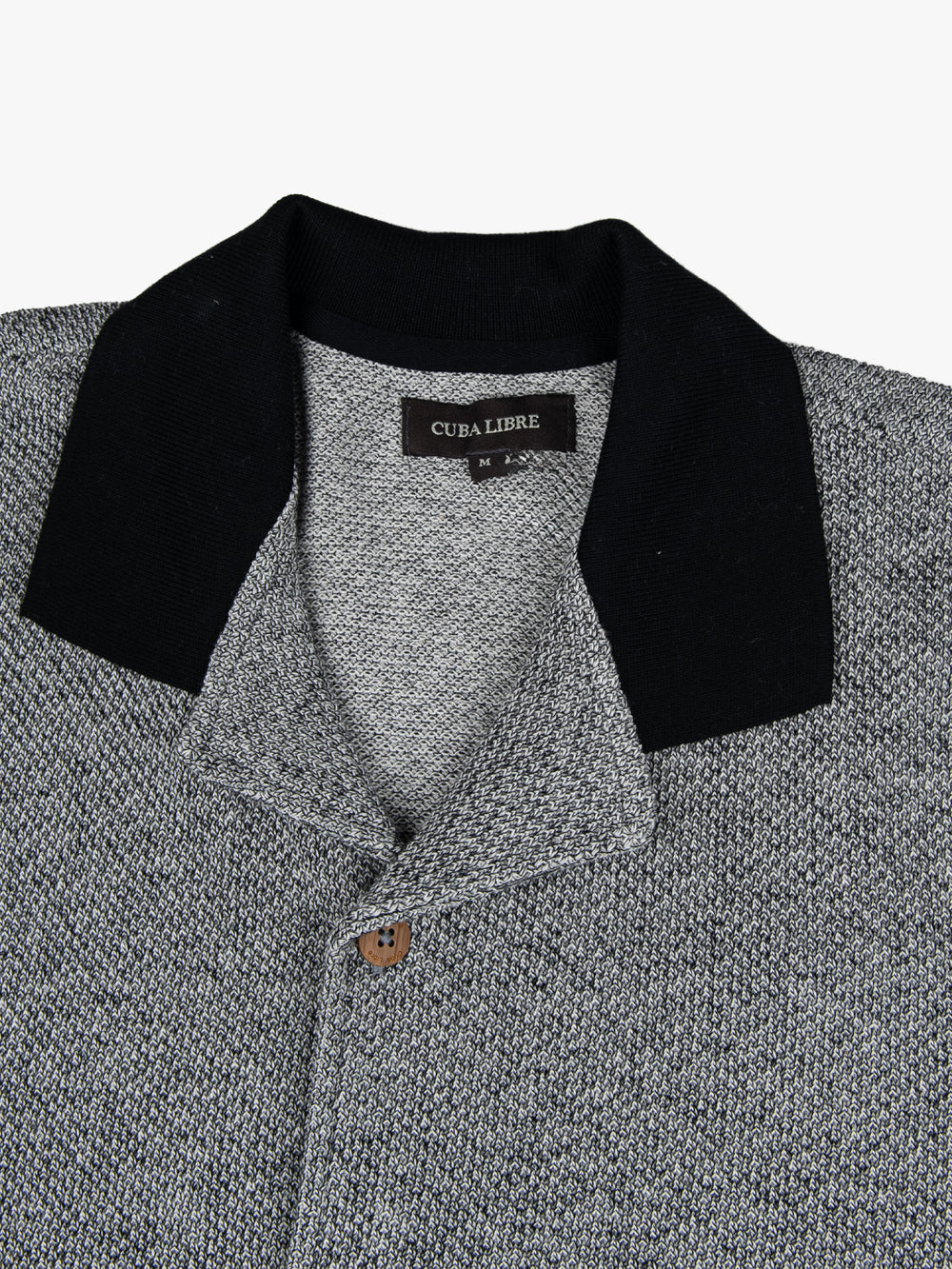 Close-up of the black contrast collar and button detail on the Cuba Libre Bastion Knit Shirt in Black by Partisan and Co