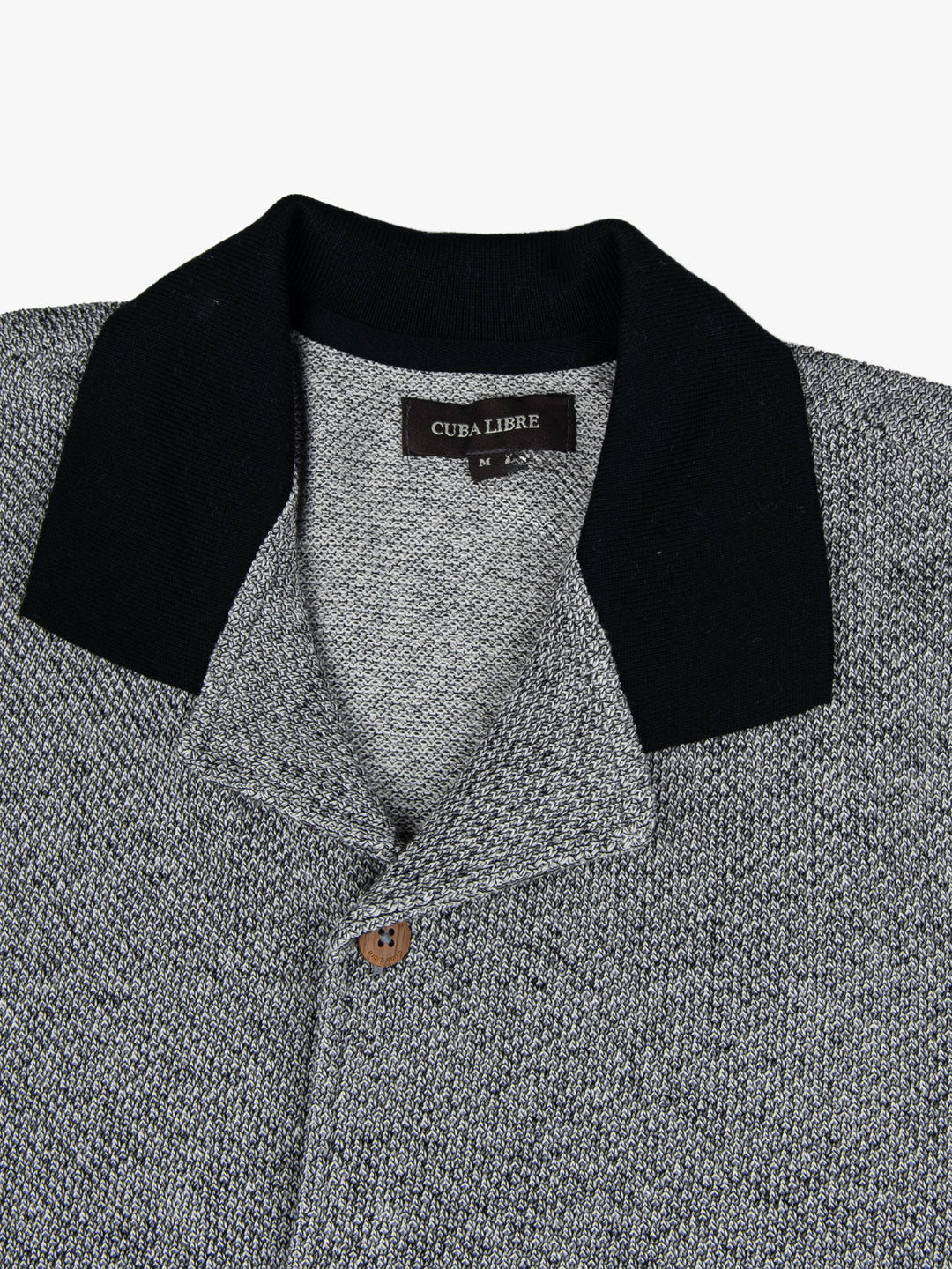 Close-up of the black contrast collar and button detail on the Cuba Libre Bastion Knit Shirt in Black by Partisan and Co