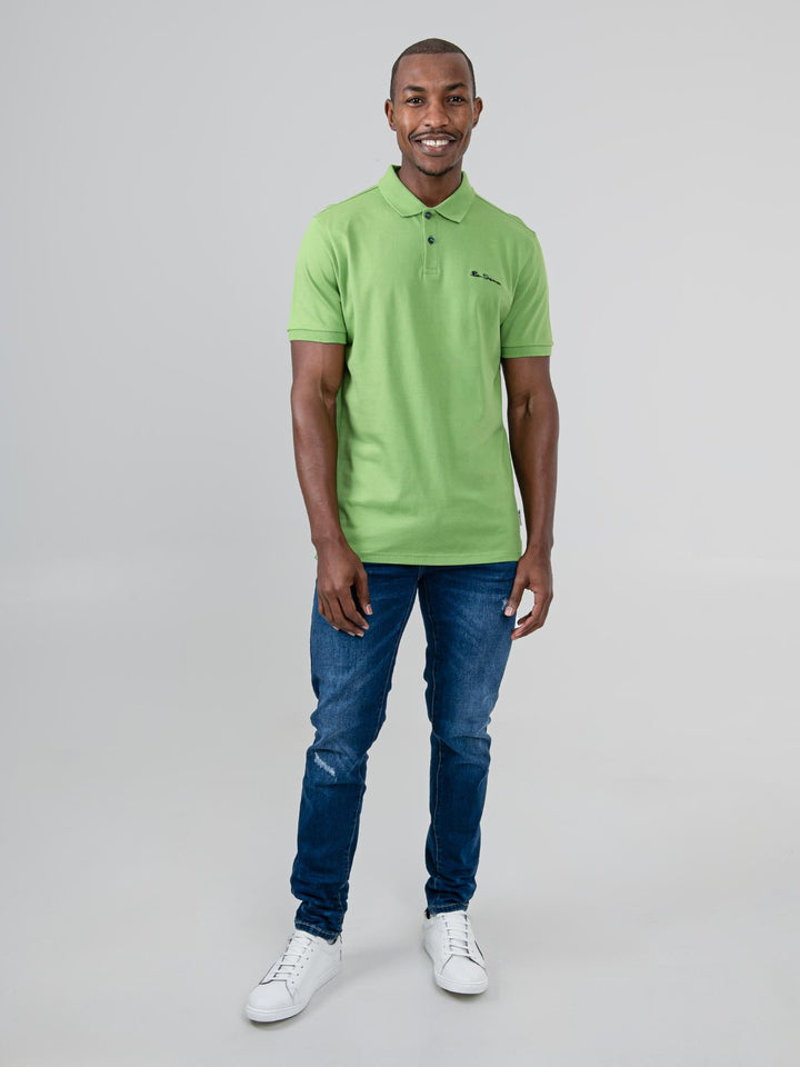 Ben Sherman Ben Polo in Piquant Green - model wearing back view showing polo shirt fiBen Sherman Ben Polo in Piquant Green - flat lay front view showing Ben Sherman Ben Polo in Piquant Green - flat lay close-up showing collar detail and Ben Sherman branding on white backgroundpique cotton fabric and two-button placket on white backgroundt