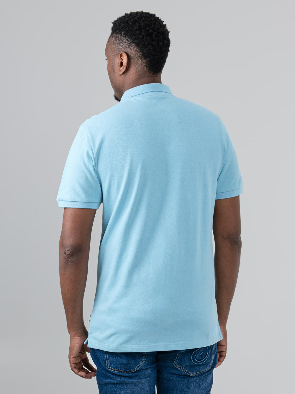 Ben Sherman Ben Polo in Retro Blue - close-up detail showing embroidered Ben Sherman script chest logo on pique cottonBen Sherman Ben Polo in Retro Blue - model wearing side angle view showing flat knit collar and short sleeve detBen Sherman Ben Polo in Retro Blue - model wearing back view showing polo shirt fitailBen Sherman Ben Polo in Retro Blue - flat lay front view showing pique cotton fabric and two-button placket on white bacBen Sherman Ben Polo in Retro Blue - flat lay close-up showing collarkground