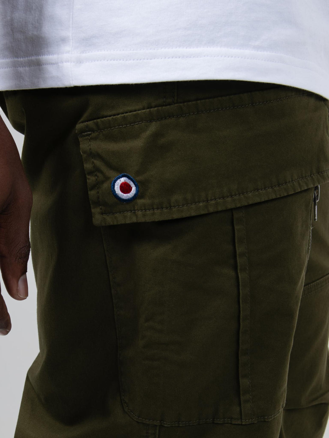 Close-up of Ben Sherman olive cargo pants pocket with signature target logo badge