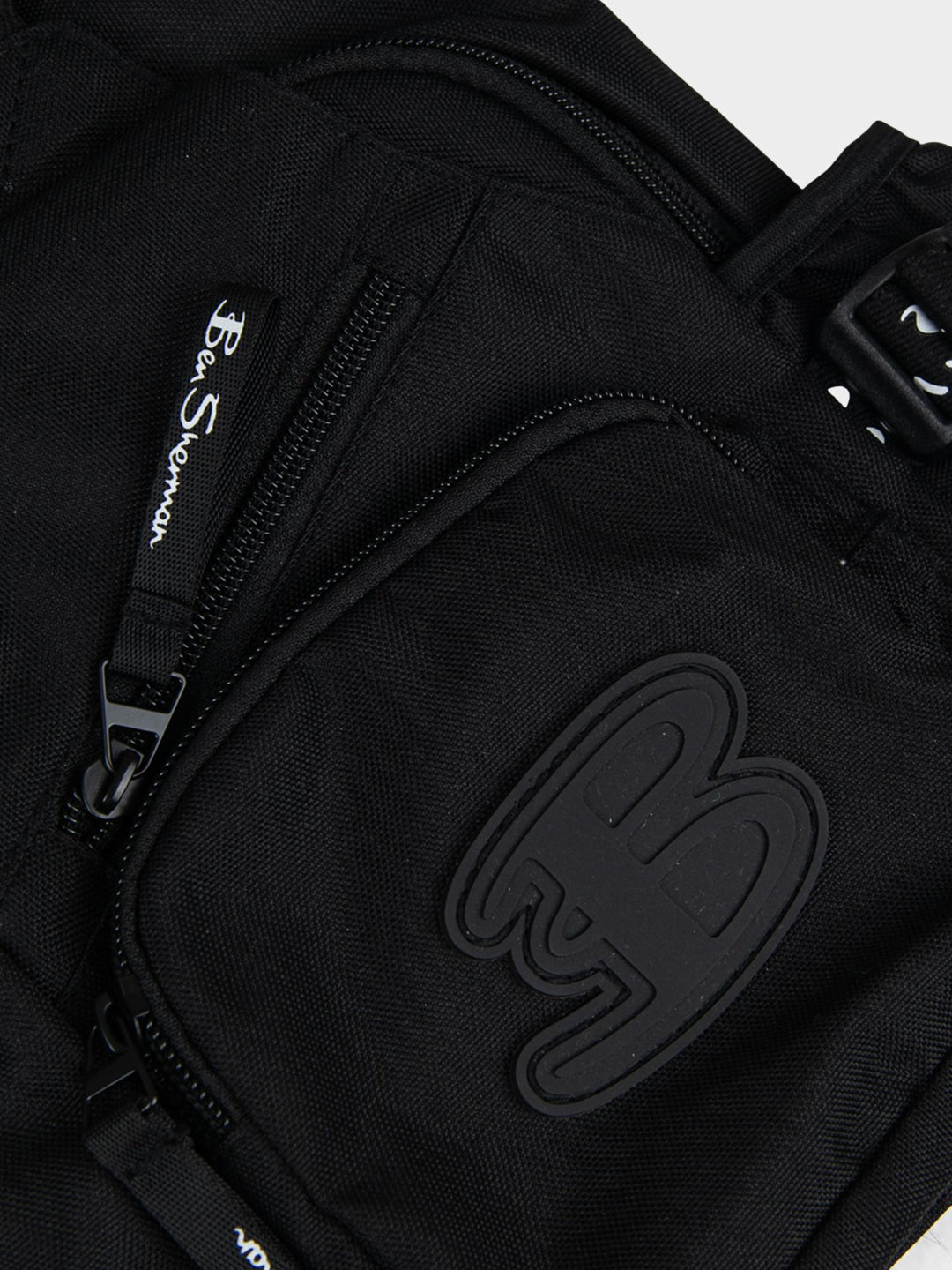 Ben Sherman Chestpack Satchel Black — close-up of canvas front pocket with embossed B logo and zip detail