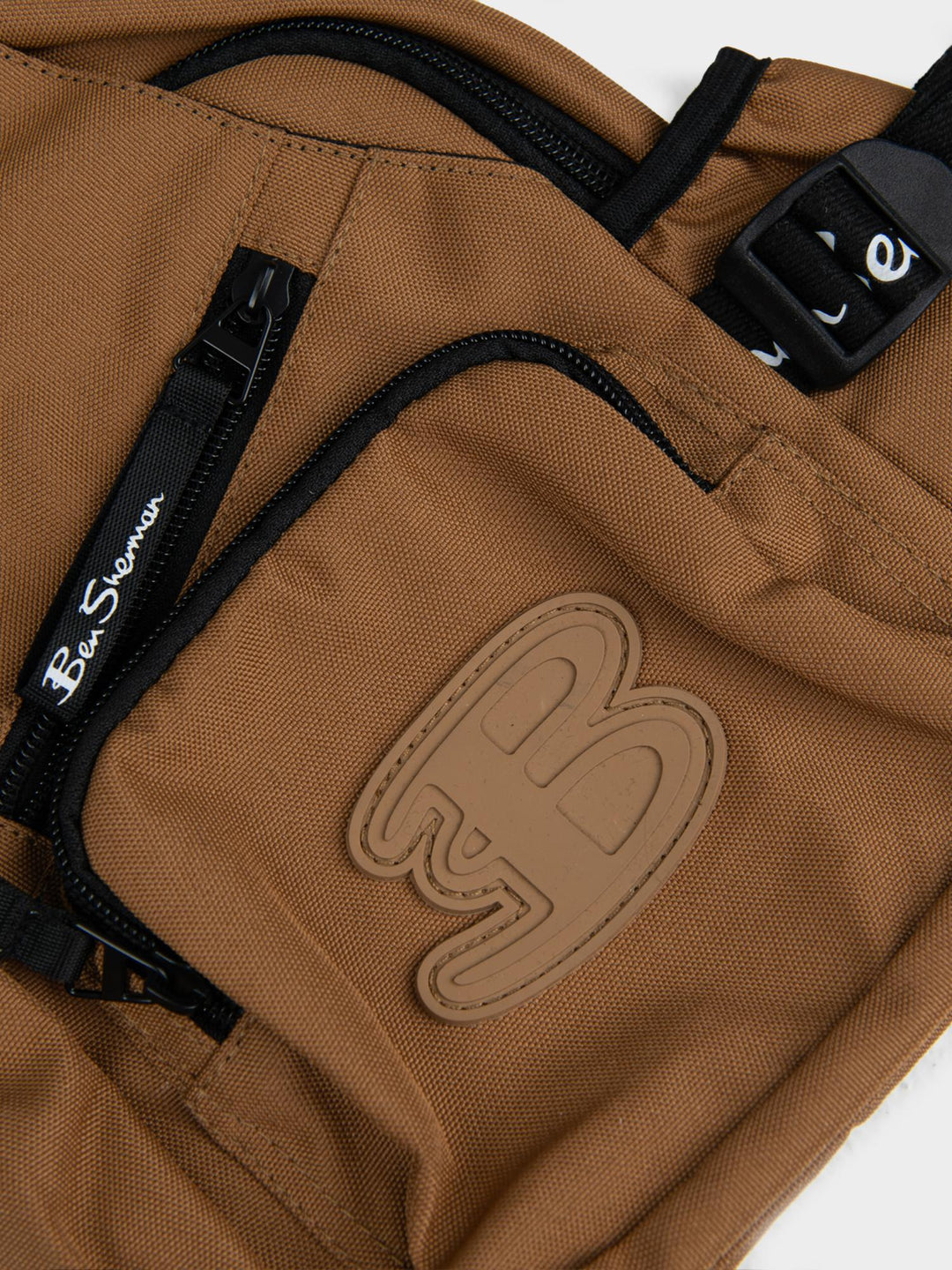 Ben Sherman Chestpack Satchel Medal Bronze — close-up of canvas front pocket with embossed B logo and zip detail