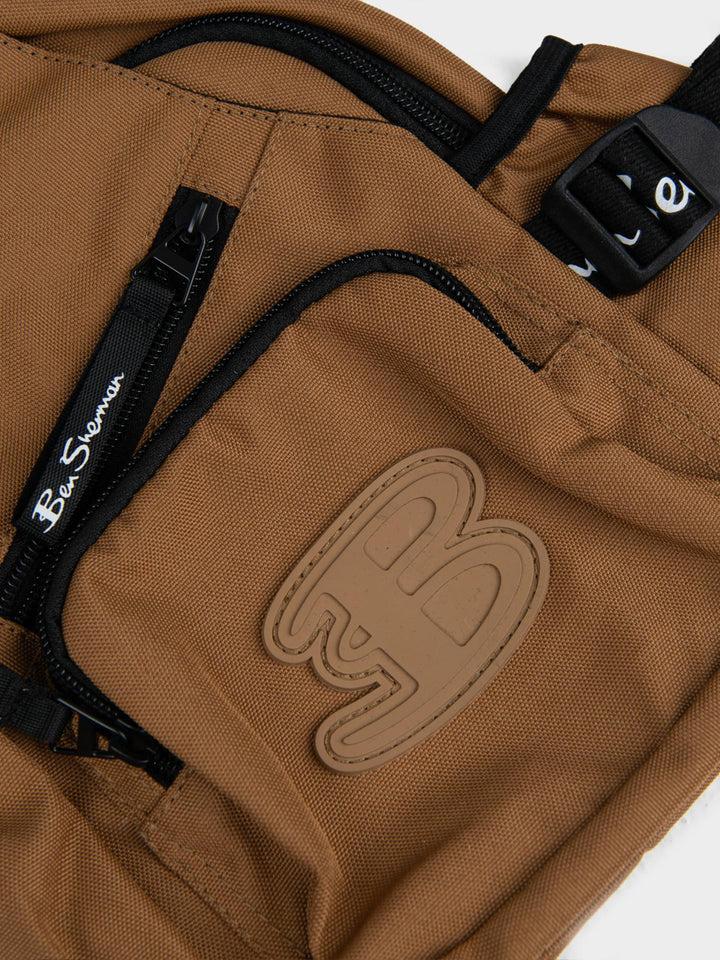 Ben Sherman Chestpack Satchel Medal Bronze — close-up of canvas front pocket with embossed B logo and zip detail
