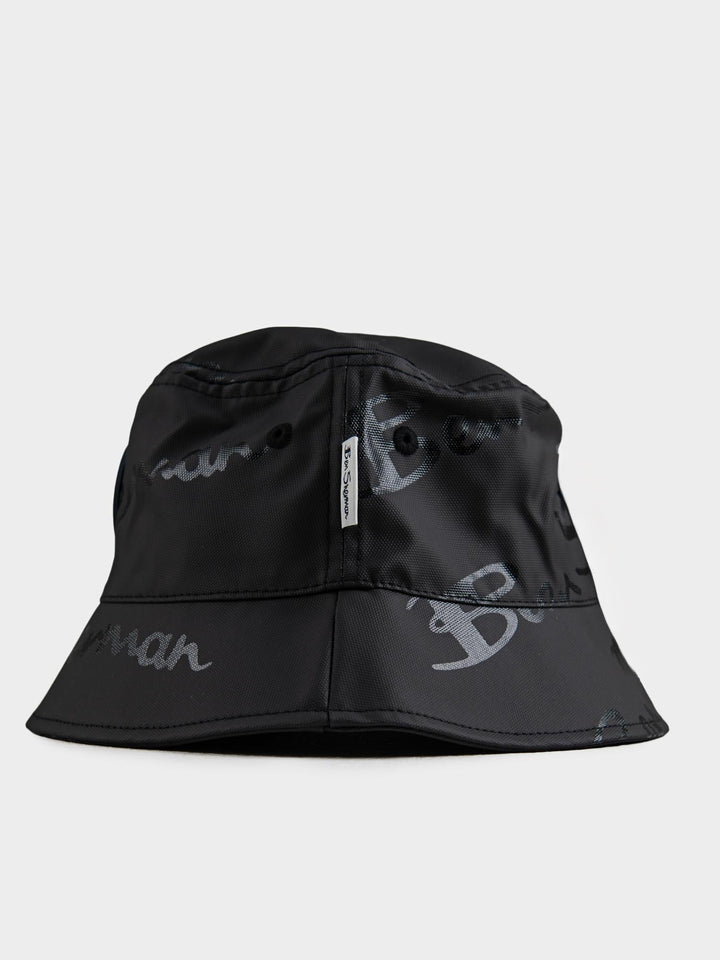 Ben Sherman reversible cotton bucket hat in Black – angled side view showing brim shape and all-over script pattern