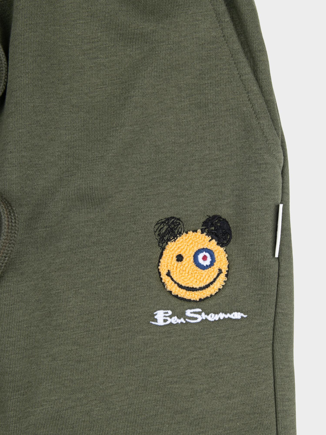 Close-up of embroidered Happy Bear motif and Ben Sherman logo on tundra green fleece jog shorts
