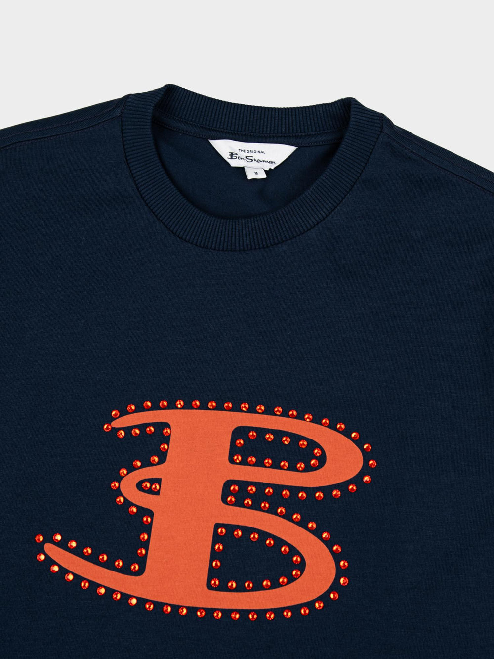 Ben Sherman B Bling Tee in Navy - close-up of rhinestone 'B' logo embellishment on chest with branded label