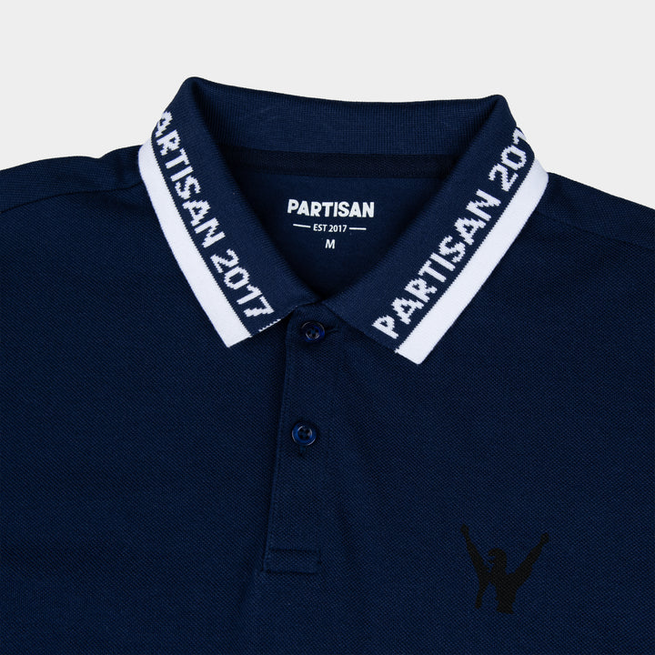 Close-up of Partisan 2017 Polo collar in Sprink Navy — woven branding detail and chest emblem on navy piqué fabric
