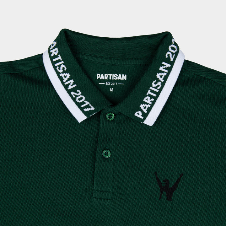 Close-up of Partisan 2017 Polo collar in Vintage Pine — woven branding detail and chest emblem on green piqué fabric