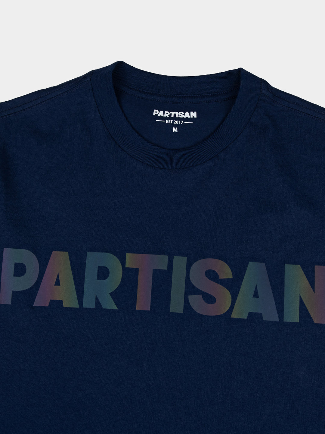 Partisan Reflective Print Tee in Navy Blue – close-up detail of the light-shifting multicolour reflective chest logo on navy streetwear t-shirt by Partisan and Co