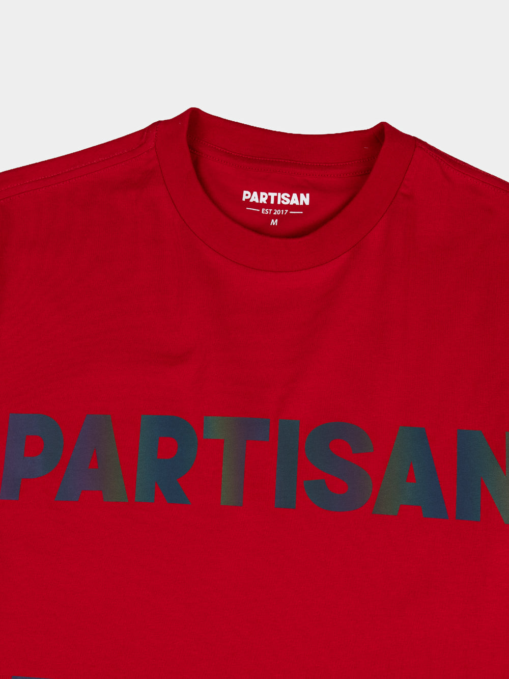 Partisan Reflective Print Tee in Red – close-up detail of the light-shifting reflective chest logo on red streetwear t-shirt by Partisan and Co
