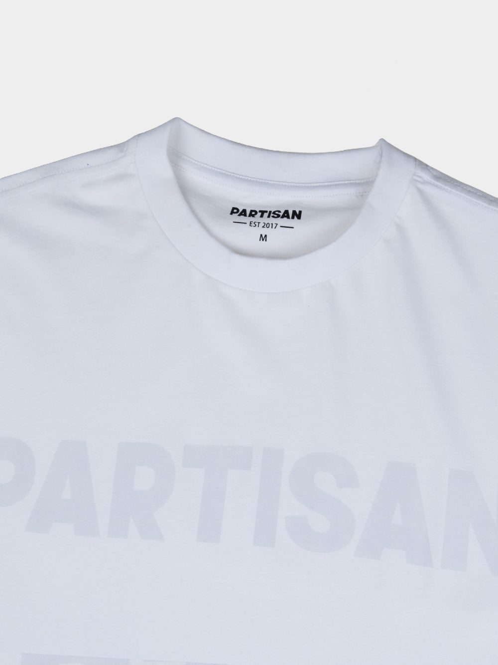 Partisan Tonal Print Tee in White – Close-up of tonal chest logo print and neck label on white cotton t-shirt