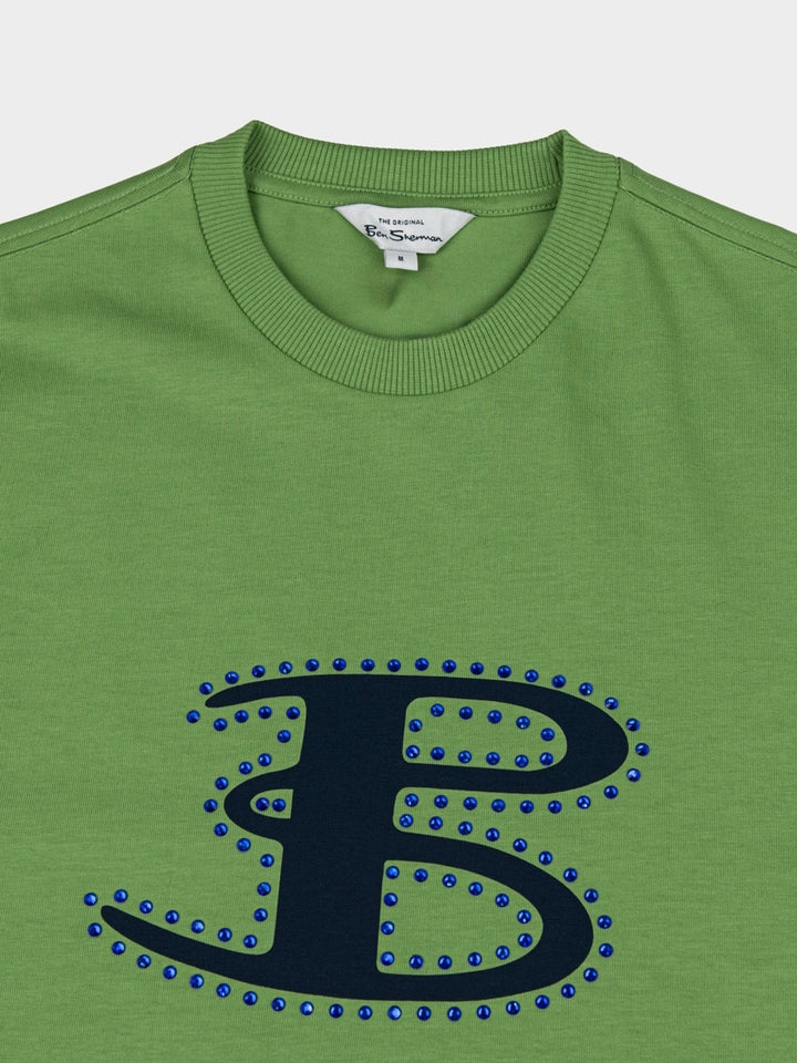Ben Sherman B Bling Tee in Piquant Green - close-up detail of rhinestone-studded B logo on green cotton tee with Ben Sherman branded crew neckline