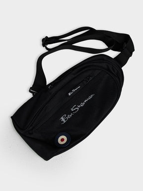 Ben Sherman Satchel Crossbody Bag in Black with multiple compartments, mesh pocket, adjustable strap and Mod target emblem – front view