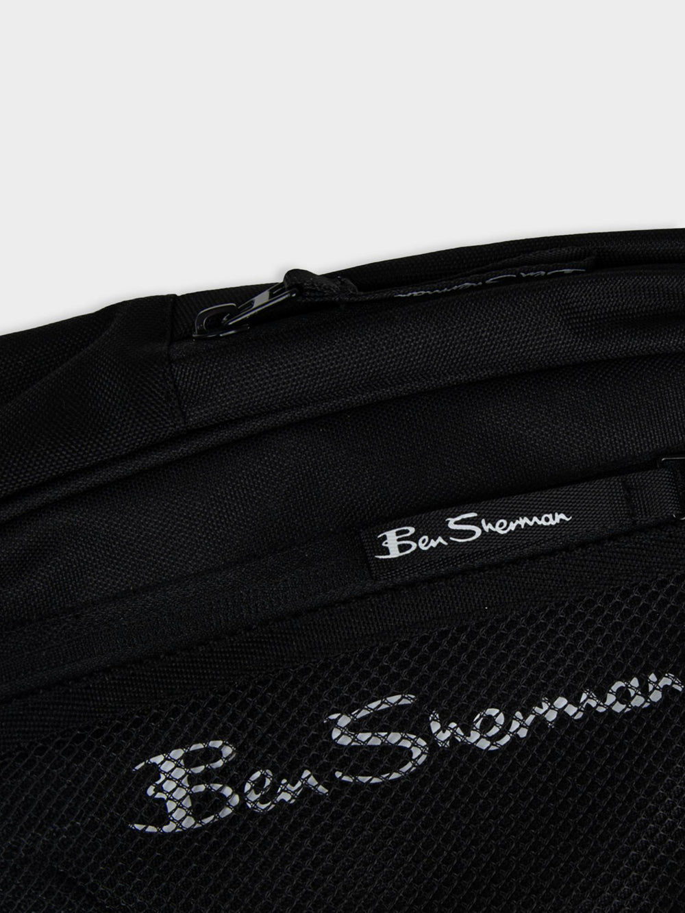 Close-up top view of Ben Sherman Satchel Crossbody in Black showing mesh pocket, zip closure and Ben Sherman script logo detail