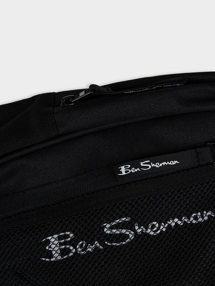 Close-up top view of Ben Sherman Satchel Crossbody in Black showing mesh pocket, zip closure and Ben Sherman script logo detail