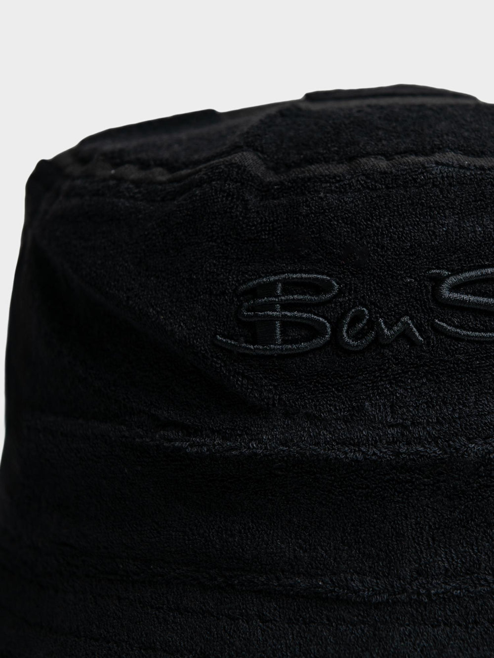 Ben Sherman Target Towelling Bucket Hat in Black - close-up of tonal embroidered Ben Sherman logo on soft black terrycloth