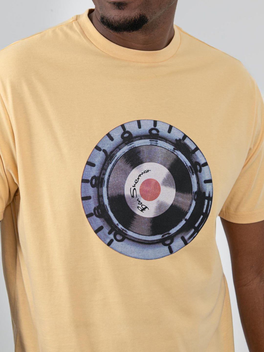 Close-up of Ben Sherman Turn It Up Tee New Wheat – retro vinyl record graphic print detail on yellow cotton fabric