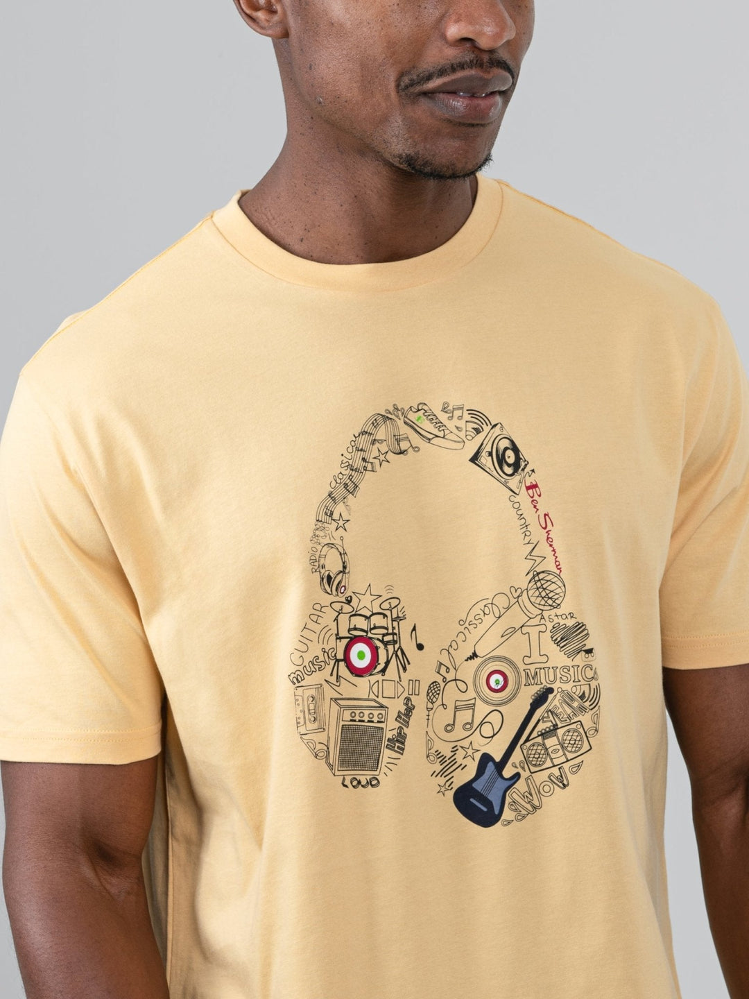aBen Sherman Typography Headphones Tee New Wheat - close-up detail of headphone graphic filled with typography, instruments and music-inspired icons