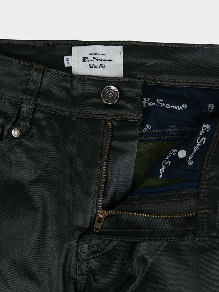 Ben Sherman Wax Coated Sheen Slim Fit Denim in Olive - close-up detail of Ben Sherman branded label, zip fly and button fastening with wax-sheen finish
